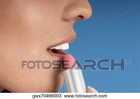 Close-up of a young woman applying lipstick View Large Photo Image Stock Image - Close-up of a young woman applying lipstick. Fotosearch