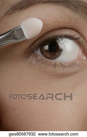 Close-up of a young woman applying eyeshadow View Large Photo Image Stock Image - Close-up of a young woman applying eyeshadow. Fotosearch