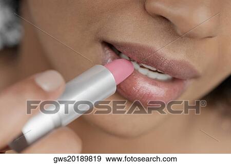 Close-up of a young woman applying lipstick View Large Photo Image Stock Photo - Close-up of a young woman applying lipstick. Fotosearch