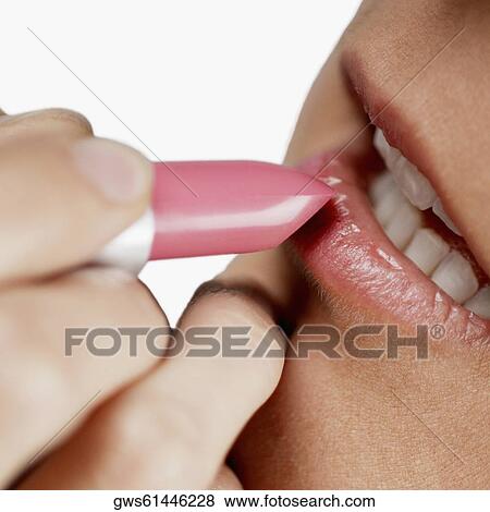 Close-up of a young woman applying lipstick View Large Photo Image Stock Photo - Close-up of a young woman applying lipstick. Fotosearch