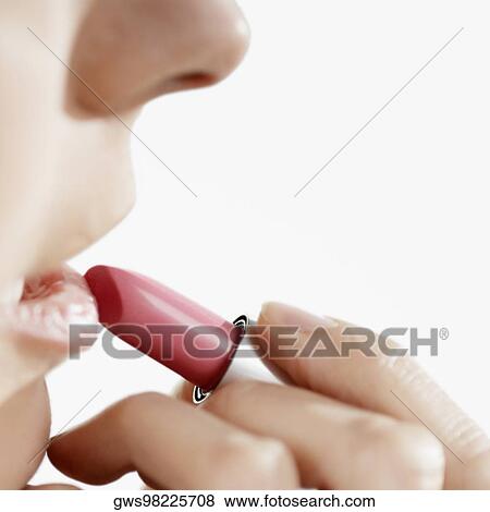 Close-up of a young woman applying lipstick View Large Photo Image Stock Photo - Close-up of a young woman applying lipstick. Fotosearch