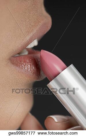 Close-up of a young woman applying lipstick View Large Photo Image Stock Photo - Close-up of a young woman applying lipstick. Fotosearch