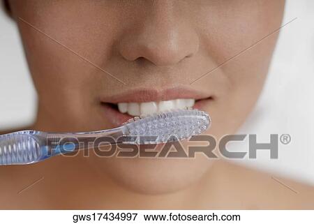 Close-up of a young woman brushing her teeth View Large Photo Image Stock Photo - Close-up of a young woman brushing her teeth. Fotosearch