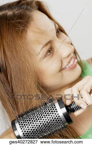 Close-up of a young woman brushing her hair View Large Photo Image Stock Photo - Close-up of a young woman brushing her hair. Fotosearch