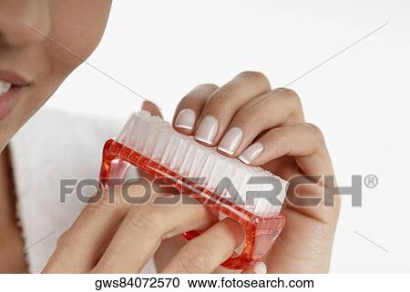 Stock Image - Close-up of a young woman cleaning her fingernails with a nail brush. Fotosearch