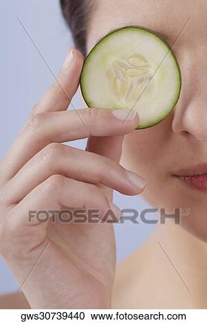 Close-up of a young woman covering her eye with a cucumber slice View Large Photo Image Stock Image - Close-up of a young woman covering her eye with a cucumber slice. Fotosearch