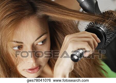 Close-up of a young woman drying her hair with a hair dryer View Large Photo Image Stock Photograph - Close-up of a young woman drying her hair with a hair dryer. Fotosearch