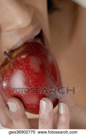 Stock Image - Close-up of a young woman eating an apple. Fotosearch