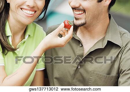 Close-up of a young woman feeding a strawberry to a young man View Large Photo Image Stock Image - Close-up of a young woman feeding a strawberry to a young man. Fotosearch