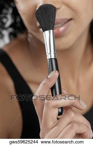 Close-up of a young woman holding a blush brush View Large Photo Image Picture - Close-up of a young woman holding a blush brush. Fotosearch