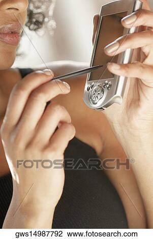 Stock Image - Close-up of a young woman holding a mobile phone and a stylus. Fotosearch