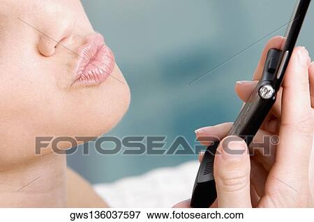 Stock Photo - Close-up of a young woman holding a mobile phone. Fotosearch