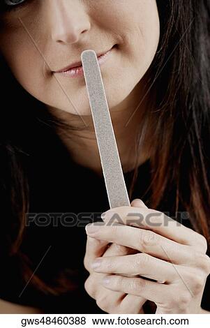 Close-up of a young woman holding a nail file View Large Photo Image Stock Photo - Close-up of a young woman holding a nail file. Fotosearch