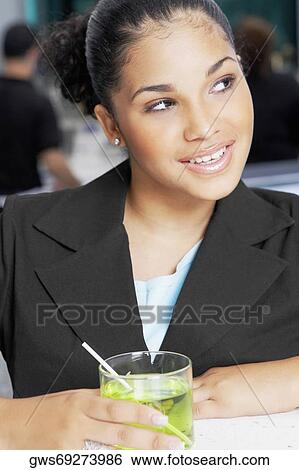 Stock Photograph - Close-up of a young woman holding a glass of cocktail. Fotosearch