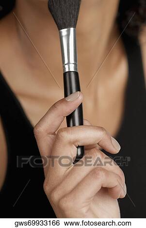 Close-up of a young woman holding a blush brush View Large Photo Image Stock Photograph - Close-up of a young woman holding a blush brush. Fotosearch