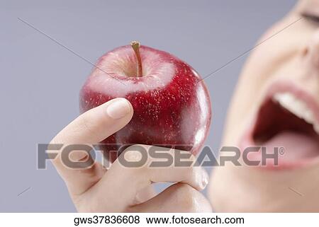 Stock Photo - Close-up of a young woman holding an apple. Fotosearch
