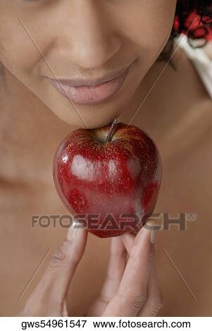 Close-up of a young woman holding an apple under her chin View Large Photo Image Stock Photo - Close-up of a young woman holding an apple under her chin. Fotosearch