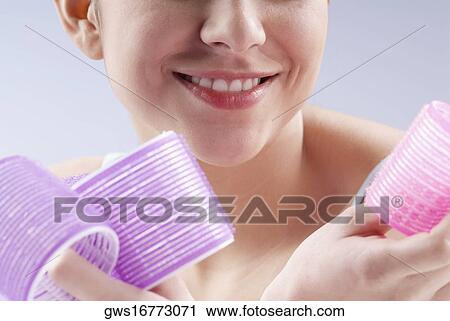 Close-up of a young woman holding hair curlers and smiling View Large Photo Image Stock Image - Close-up of a young woman holding hair curlers and smiling. Fotosearch