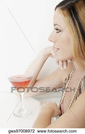 Close-up of a young woman in front of a glass of martini View Large Photo Image Stock Image - Close-up of a young woman in front of a glass of martini. Fotosearch