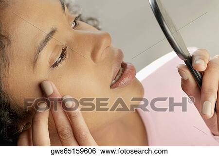 Close-up of a young woman looking into a hand mirror View Large Photo Image Stock Photograph - Close-up of a young woman looking into a hand mirror. Fotosearch