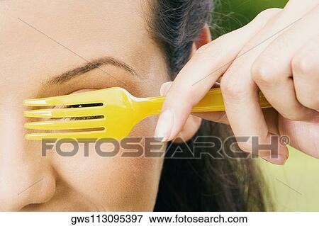 Close-up of a young woman peeking through a fork View Large Photo Image Stock Photo - Close-up of a young woman peeking through a fork. Fotosearch