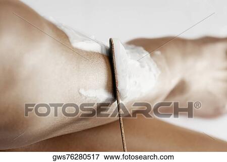 Stock Photo - Close-up of a young woman removing cream from her leg. Fotosearch