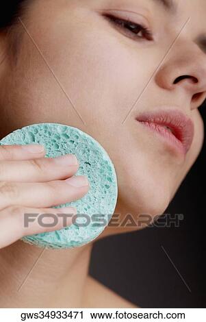 Close-up of a young woman scrubbing her face with a sponge View Large Photo Image Stock Image - Close-up of a young woman scrubbing her face with a sponge. Fotosearch