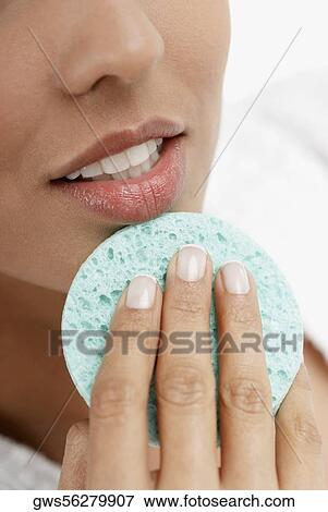 Close-up of a young woman scrubbing her chin with a sponge View Large Photo Image Stock Photo - Close-up of a young woman scrubbing her chin with a sponge. Fotosearch