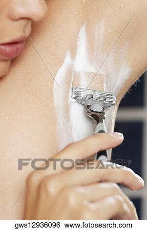 Stock Photograph - Close-up of a young woman shaving her armpit. Fotosearch