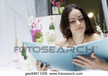 Close-up of a young woman sitting in a restaurant and reading a menu View Large Photo Image Stock Photograph - Close-up of a young woman sitting in a restaurant and reading a menu. Fotosearch