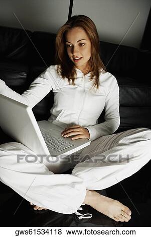 Stock Photo - Close-up of a young woman sitting on the floor and using a laptop. Fotosearch