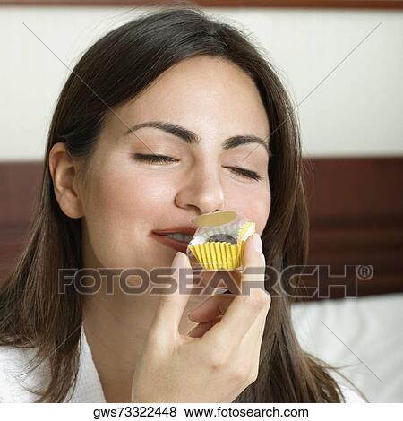 Close-up of a young woman smelling a cupcake View Large Photo Image Stock Photo - Close-up of a young woman smelling a cupcake. Fotosearch