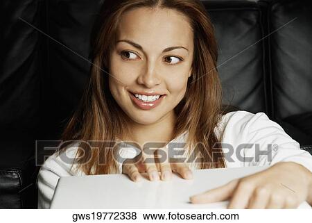 Stock Photo - Close-up of a young woman smiling and looking away. Fotosearch