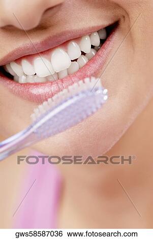 Close-up of a young woman smiling with a toothbrush in front of her mouth View Large Photo Image Stock Photograph - Close-up of a young woman smiling with a toothbrush in front of her mouth. Fotosearch