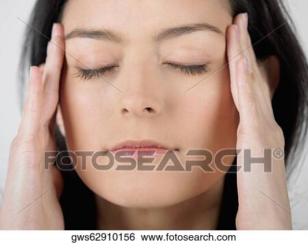 Stock Photograph - Close-up of a young woman touching her temples. Fotosearch