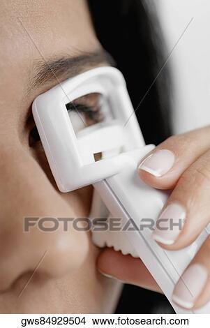 Close-up of a young woman using an eyelash curler View Large Photo Image Picture - Close-up of a young woman using an eyelash curler. Fotosearch