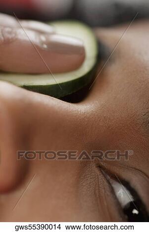 Close-up of a young woman with a cucumber slice on her eye View Large Photo Image Picture - Close-up of a young woman with a cucumber slice on her eye. Fotosearch