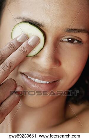Close-up of a young woman with a cucumber slice on her eye View Large Photo Image Stock Image - Close-up of a young woman with a cucumber slice on her eye. Fotosearch
