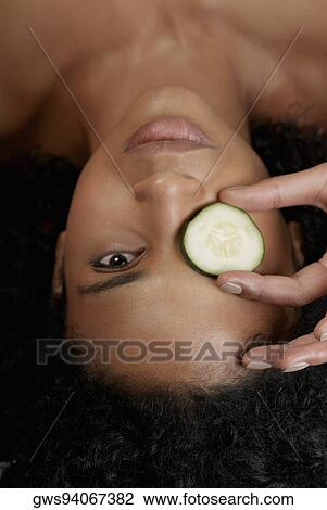 Close-up of a young woman with a cucumber slice on her eye View Large Photo Image Stock Image - Close-up of a young woman with a cucumber slice on her eye. Fotosearch