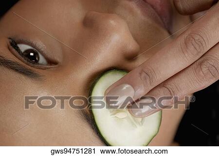 Close-up of a young woman with a cucumber slice on her eye View Large Photo Image Stock Image - Close-up of a young woman with a cucumber slice on her eye. Fotosearch