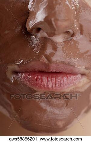 Stock Image - Close-up of a young woman's face with a facial mask. Fotosearch