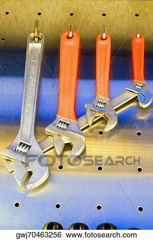 Stock Photograph - Close-up of four adjustable wrenches hanging from hooks. Fotosearch