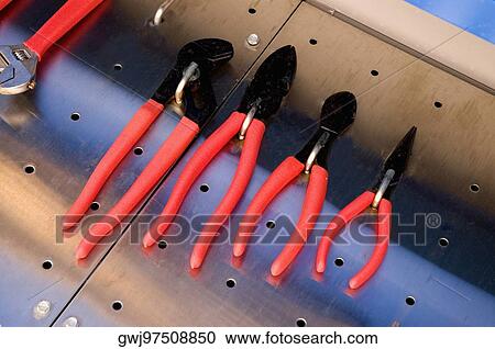 Stock Image - Close-up of hand tools hanging from hooks. Fotosearch
