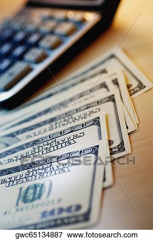 Close-up of one hundred dollar bill with a calculator View Large Photo Image Stock Photo - Close-up of one hundred dollar bill with a calculator. Fotosearch