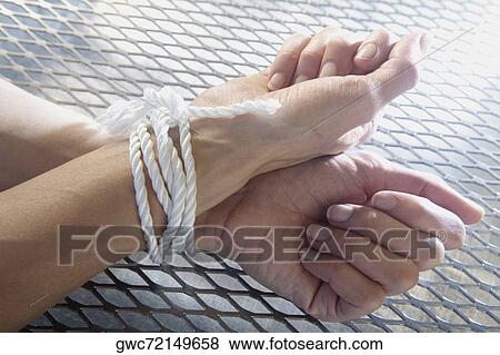 Stock Photo - Close-up of person's hands tied with rope. Fotosearch