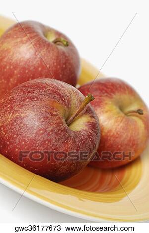 Stock Image - Close-up of three apples in a tray. Fotosearch