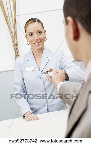 Customer giving a credit card to a female receptionist View Large Photo Image Stock Image - Customer giving a credit card to a female receptionist. Fotosearch