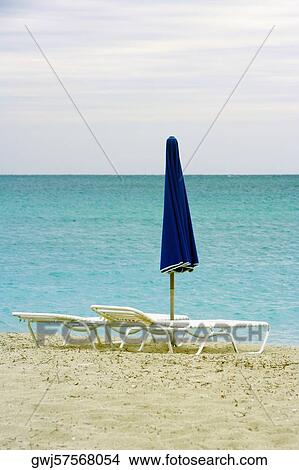 Empty lounge chair and a folded beach umbrella on the beach View Large Photo Image Picture - Empty lounge chair and a folded beach umbrella on the beach. Fotosearch