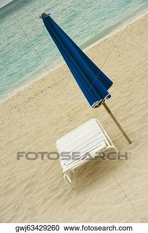 Empty lounge chair and a folded beach umbrella on the beach View Large Photo Image Stock Image - Empty lounge chair and a folded beach umbrella on the beach. Fotosearch