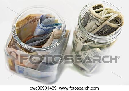 Stock Photo - Euro and American bank notes squashed into two jars. Fotosearch